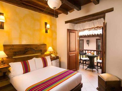 A room at one of the Cartagena boutique hotels with a bed with colorful sheets and doors open to a balcony in the background