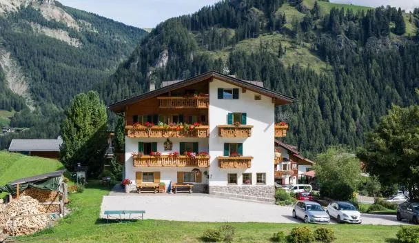 Alpine chalet with flower-box balconies, stone base and firewood pile, with on-site parking and forested mountain views at Villa Insam in Selva di Val Gardena