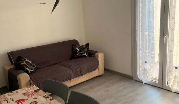 Living area with patterned sofa, wall decal 'un sorriso un giorno perso!', round dining table and sliding glass door at At Home Mestre Via Nigra Venezia 3 bedrooms & parking free in Mestre