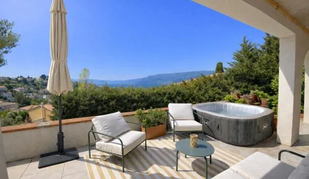 Terrace with inflatable hot tub, striped rug, two cushioned armchairs and parasol overlooking lake and hills at Maison calme - SPA - proche Nice - Terrasse & clim in Colomars