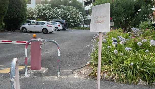 Barrier-free parking with bollards, 'Interdire' sign and landscaped beds beside a multi-story building with parking at AmazingCaulderHome in Cannes