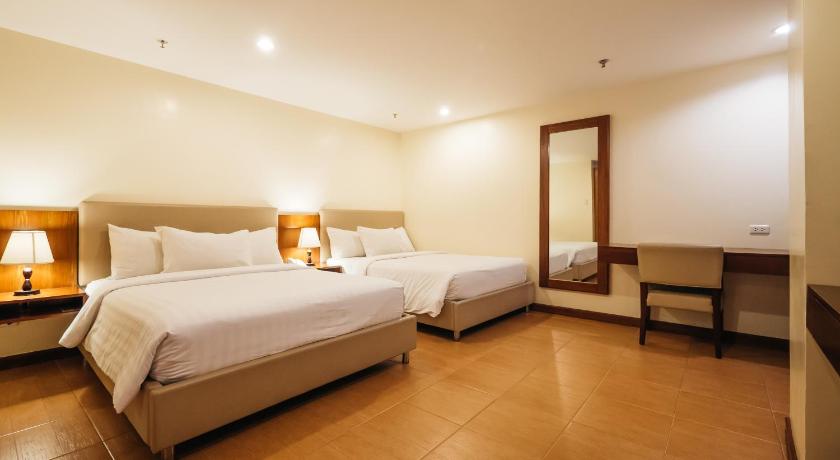 a hotel room with two beds and a television, The Well Hotel Inc in Cebu
