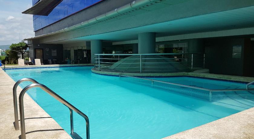 a swimming pool in a building with a blue roof, Cebu Parklane International Hotel in Cebu