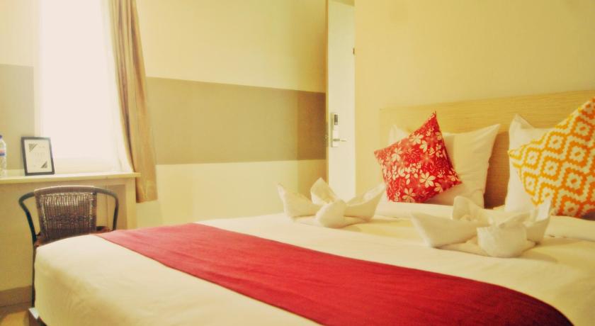 a bed room with two beds and a white comforter, Leos Hotel in Manado