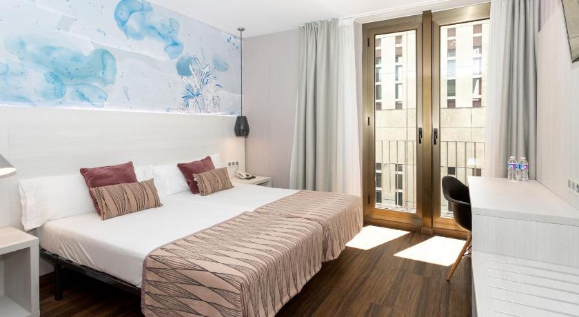 a bedroom with a bed, a desk, and a window, Hostal Operaramblas in Barcelona