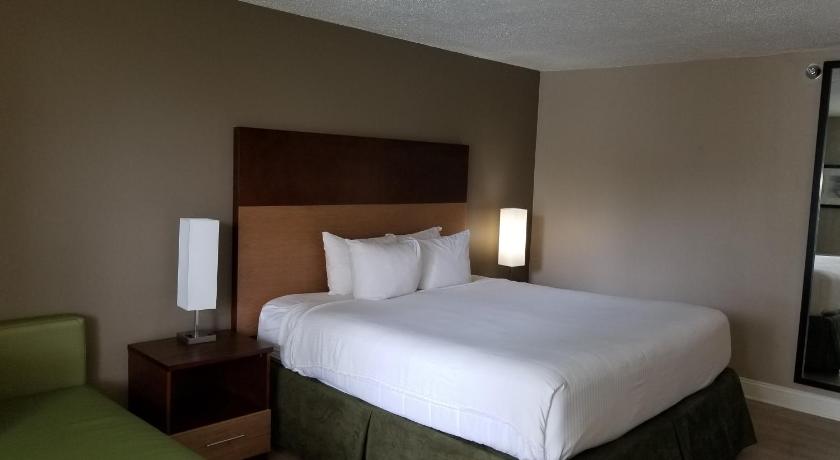 a hotel room with a bed, chair, and nightstand, Stayable Select Gainesville in Gainesville (FL)