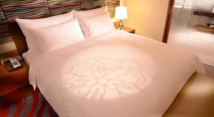 a neatly made bed with a white comforter and pillows, Fleur Lis Hotel Hsinchu in Hsinchu