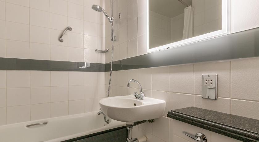 a bathroom with a sink, mirror, and bathtub, Thistle Express Luton in Luton