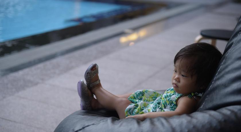 a little girl sitting on a couch holding a remote, Villa Navin Premiere Pool Villa in Pattaya