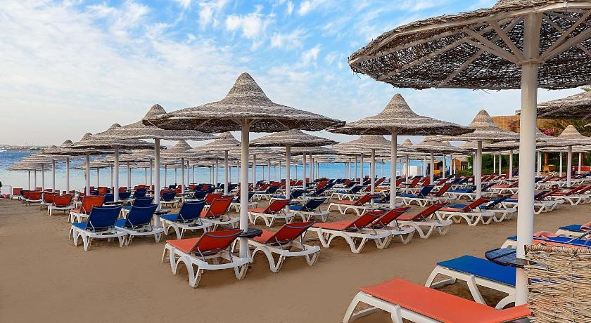 a beach area with chairs, tables and umbrellas, Prima Life Makadi in Hurghada