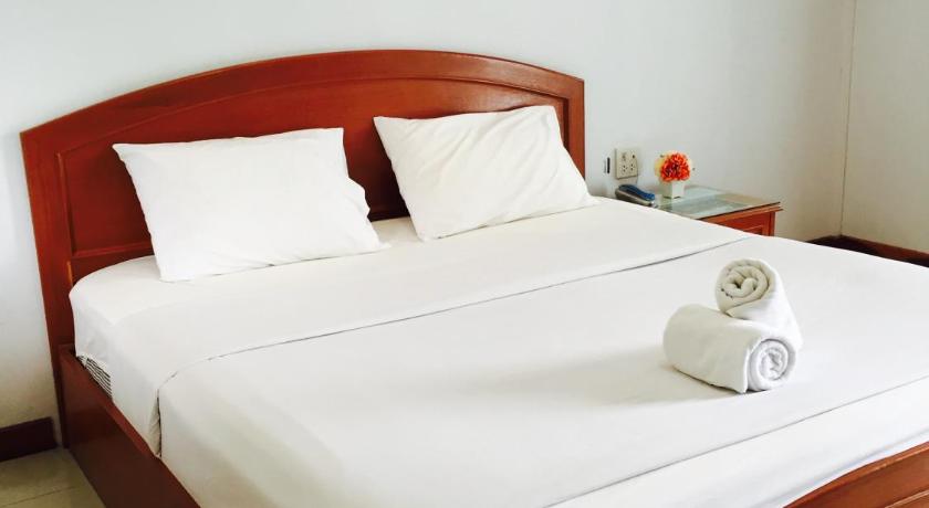 a bed with a white comforter and pillows, Panchan Place in Ubon Ratchathani