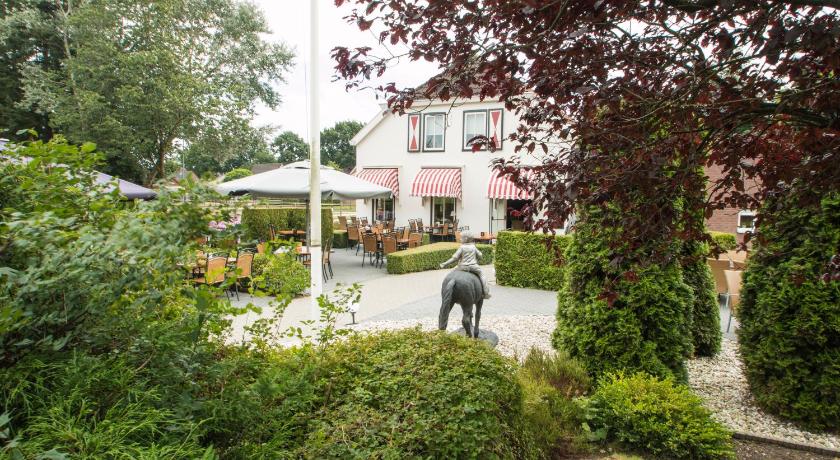 a horse standing in the middle of a grassy area, Hotel Restaurant Eeserhof in Ees