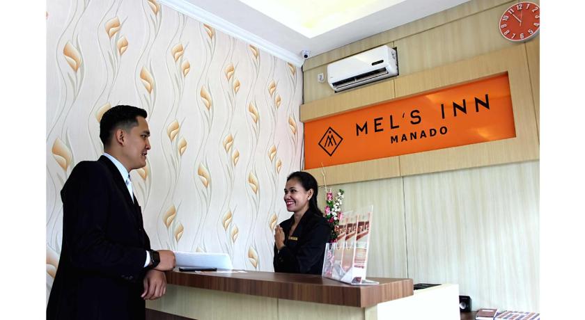 a woman standing next to a man at a counter, MEL'S INN MANADO in Manado