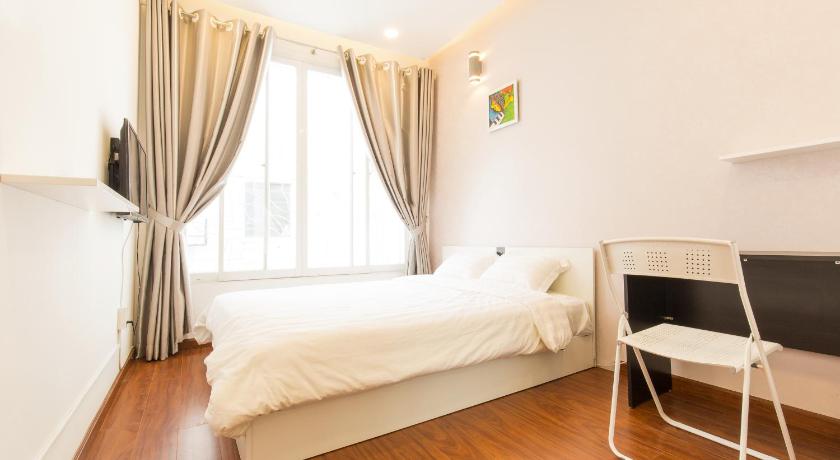 a bedroom with a white bed and a white chair, Qhome Saigon - Vo Van Tan in Ho Chi Minh City