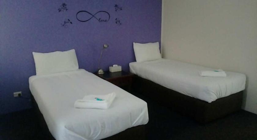 two white beds in a room with a blue wall, Blue Pacific Motel in Lake Macquarie