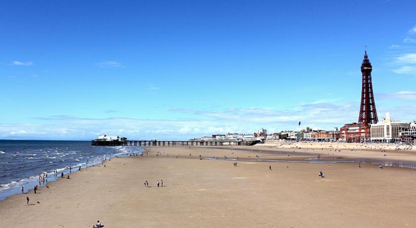 a beach with a lighthouse and some boats on it, The Royal Carlton Hotel in Blackpool