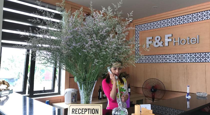 a woman standing in front of a table holding a vase of flowers, F & F Hotel in Haiphong