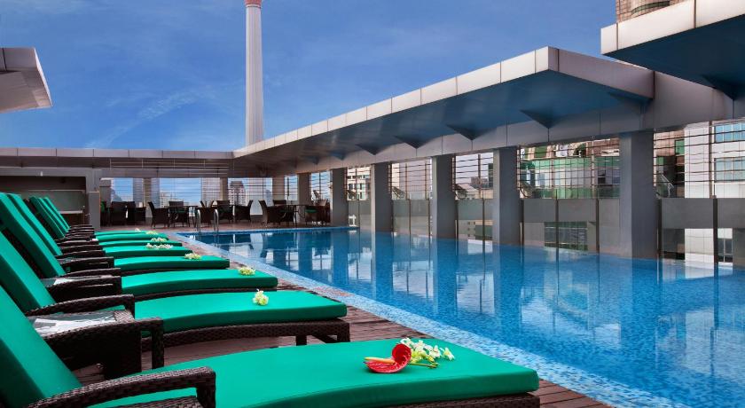 a swimming pool with blue chairs and blue umbrellas, PARKROYAL Serviced Suites Kuala Lumpur in Kuala Lumpur