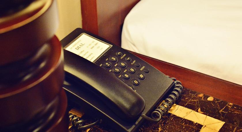 a cell phone sitting on top of a bed next to a remote control, Citystate Asturias Hotel in Palawan