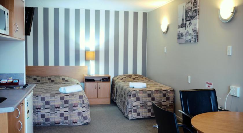 a hotel room with a bed, desk and a tv, Kiwi Studios Motel in Palmerston North