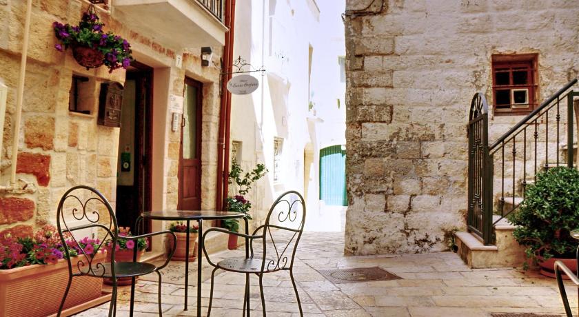 a row of wooden chairs sitting in front of a brick building, Santo Stefano Home & Breakfast in Polignano a Mare