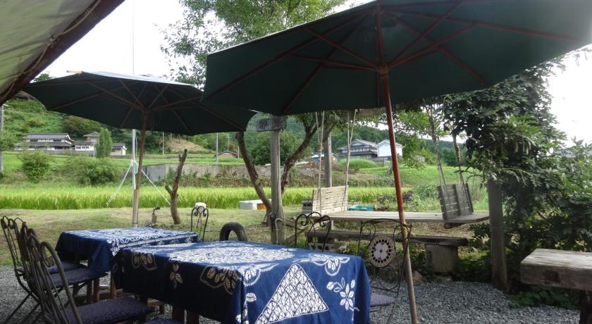 a table with umbrellas and chairs under an umbrella, 古民家の宿 ふるま家 Furumaya House Gastronomic Farmstay in Deep Kyoto in Fukuchiyama