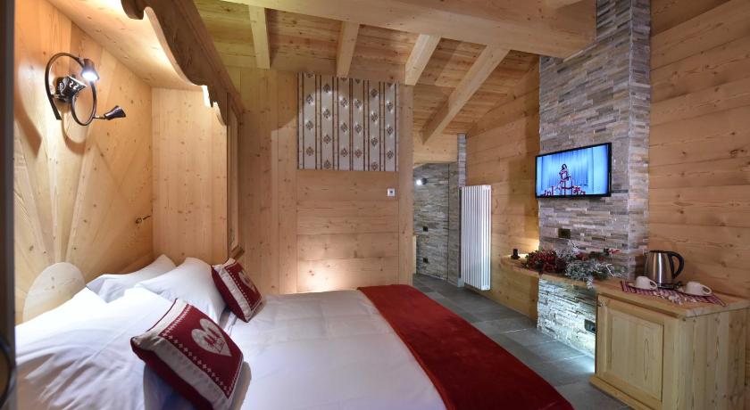 a hotel room with a bed, tv, and bedside table, Il Cuore Del Cervino in Valtournenche