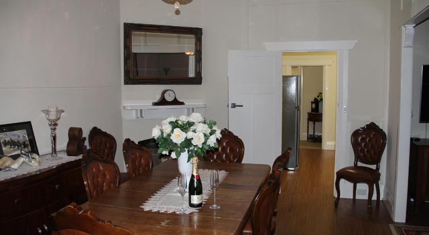 a dining room table with a vase of flowers on it, Mentor Chambers Apartment Bed & Breakfast in West Wyalong