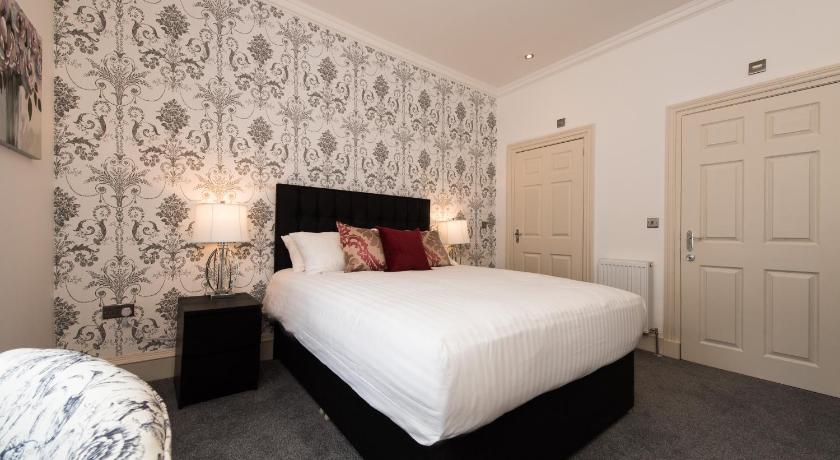 a bedroom with a bed and a dresser, Royal Princes Suites in Edinburgh