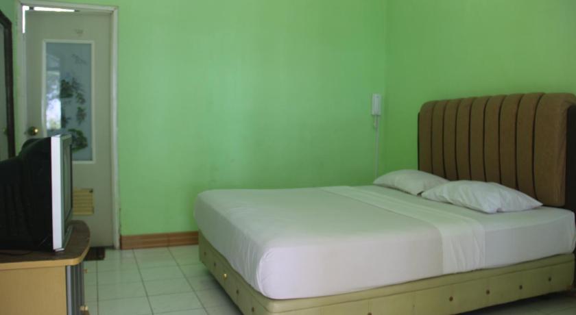 a bedroom with a bed and a dresser, Pasir Putih Resort in Bengkulu