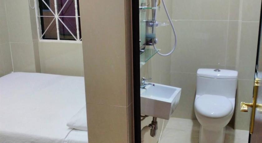 a bathroom with a toilet, sink, and shower stall, Hotel Paka INN in Paka