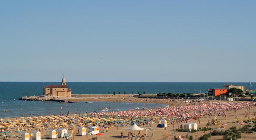 a beach filled with lots of beach chairs and umbrellas, Kinder-Hotel Villaggio dei Fiori in Caorle