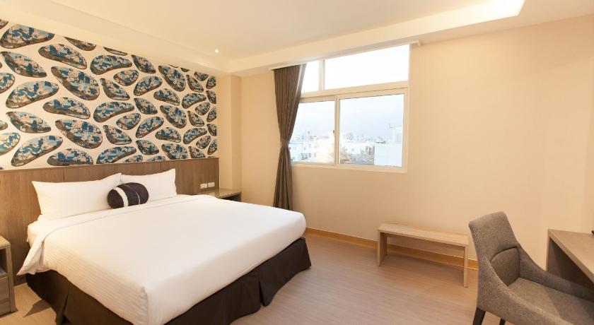 a bedroom with a white bed and white walls, TC HOTEL HUALIEN ZHONG XIAO in Hualien