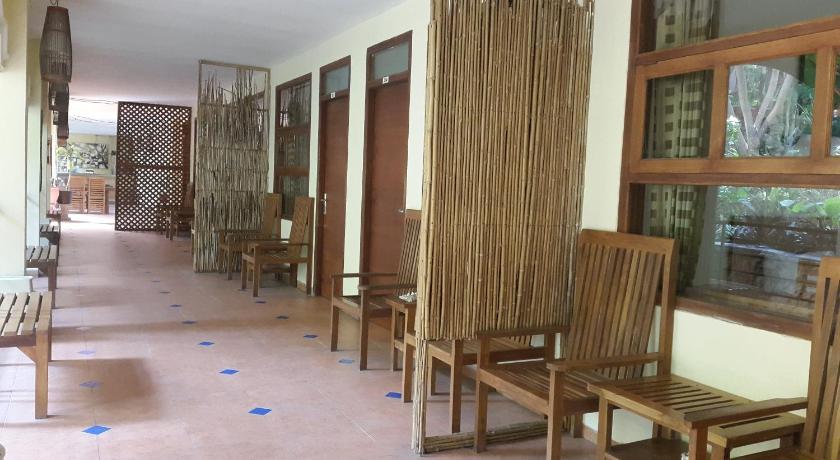 a room filled with wooden benches and chairs, Centro Bajo Hotel in Labuan Bajo