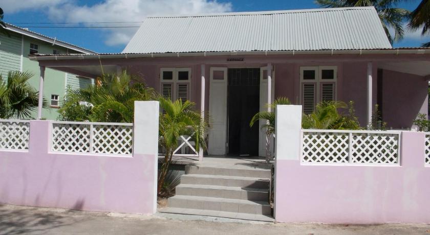 a white house with a blue door and a white fence, Beach Guest House Cleverdale in Christ Church