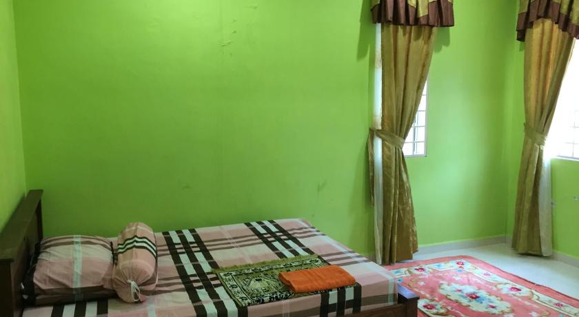 a bed in a room with a green blanket, Homestay Darulaman in Alor Setar
