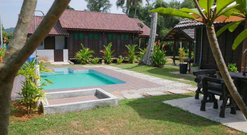 a patio area with a pool, lawn chair, and patio furniture, Kampung Tok Lembut Vacation Home in Langkawi