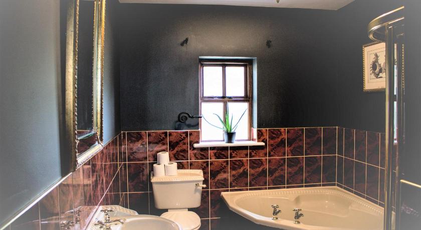 a bathroom with a tub, sink, mirror and bathtub, Storytellers Cottage in Doolin