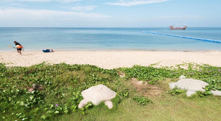 a woman sitting on a beach next to a body of water, Rawi Warin Resort & Spa (SHA Extra plus) in Koh Lanta