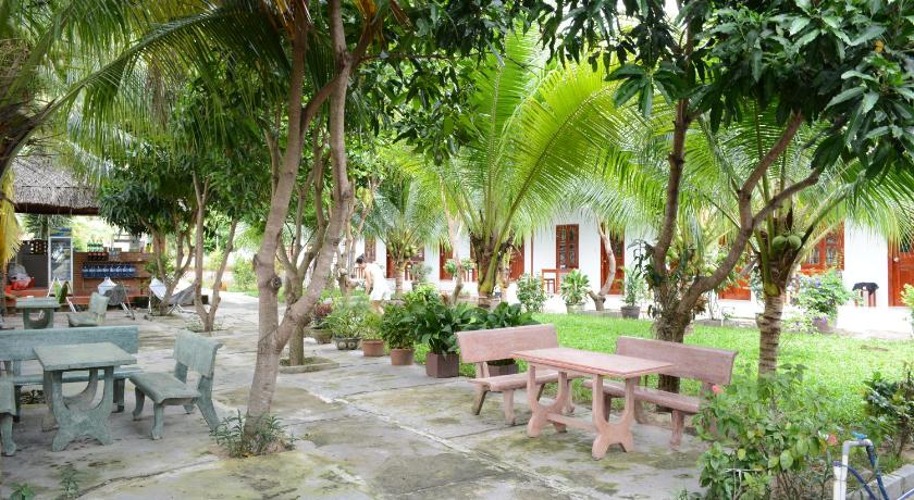 a wooden bench sitting in front of a lush green field, Diem Lien Guesthouse in Phan Thiet