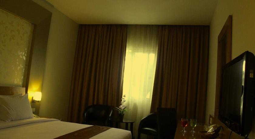 a hotel room with a bed and a television, Drego Hotel Pekanbaru in Pekanbaru