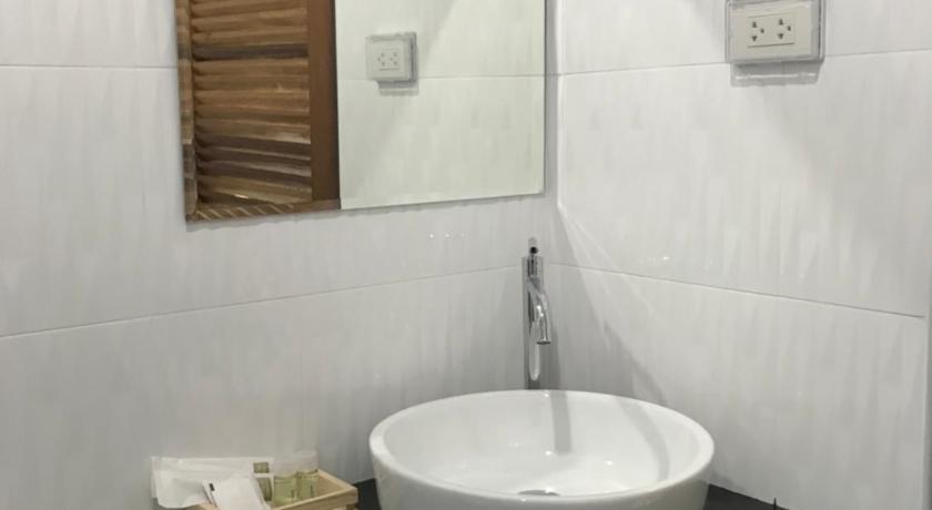 a white sink sitting under a mirror in a bathroom, Snooze Inn Phuket in Phuket