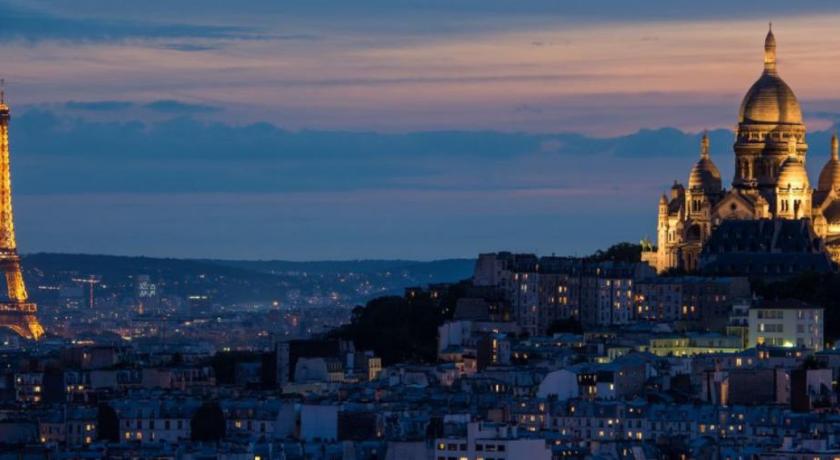 a clock tower towering over a city at night, Ateliers de Montmartre ADM in Paris