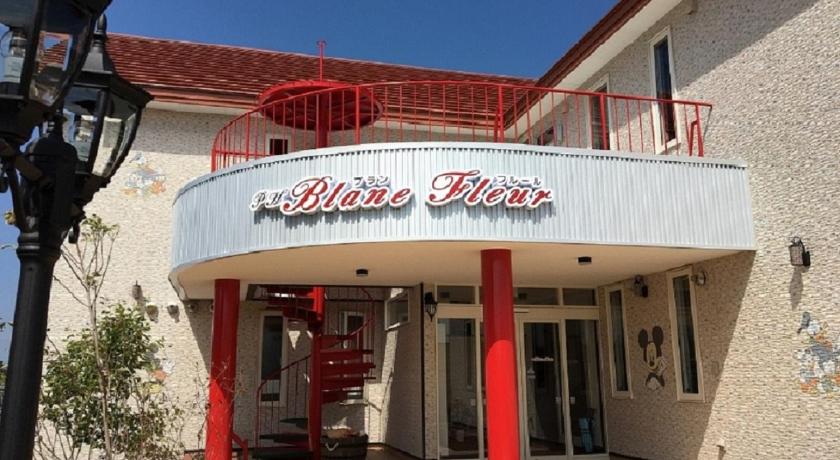 a red and white building with a sign on the front of it, Petit Hotel Blanc Fleur in Furano