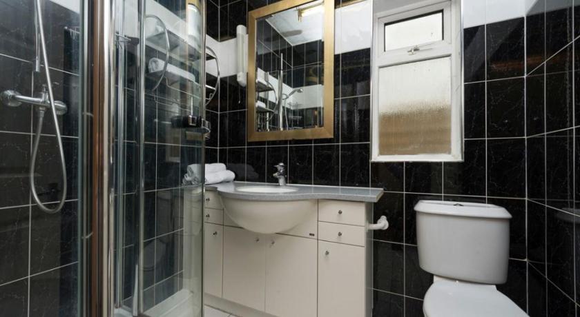 a bathroom with a toilet, sink and mirror, Golders Green Hotel in London