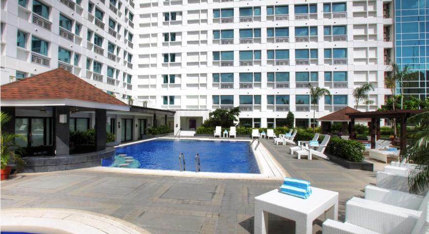 a large white swimming pool in front of a large building, Quest Serviced Residences in Cebu