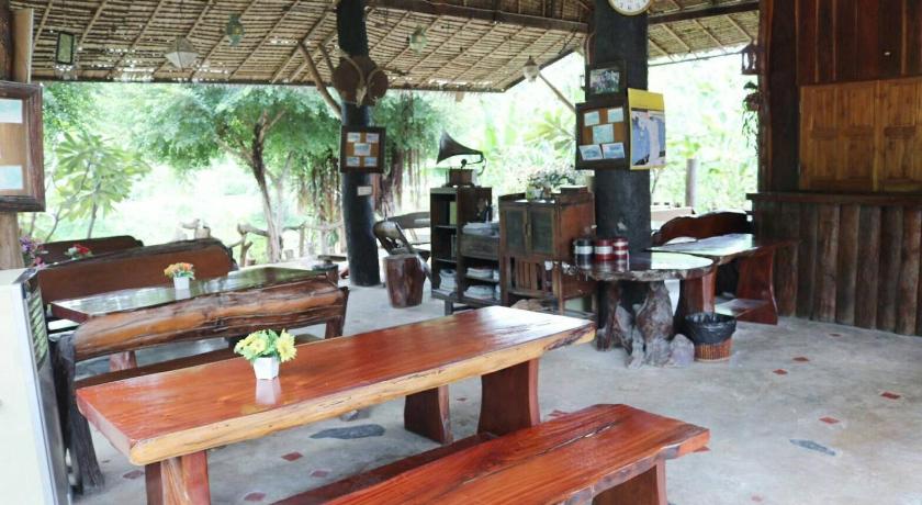 a wooden table and chairs in a wooded area, Baandin Rimnum Resort in Suphan Buri