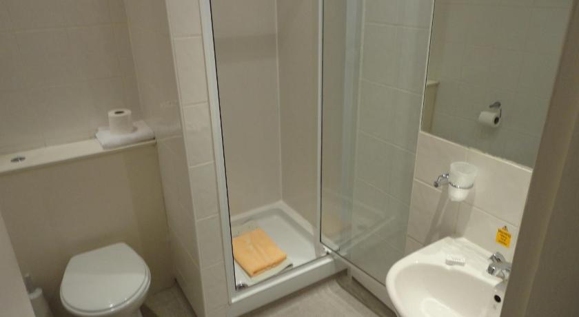 a white toilet sitting next to a shower in a bathroom, The Sandyford Hotel in Glasgow