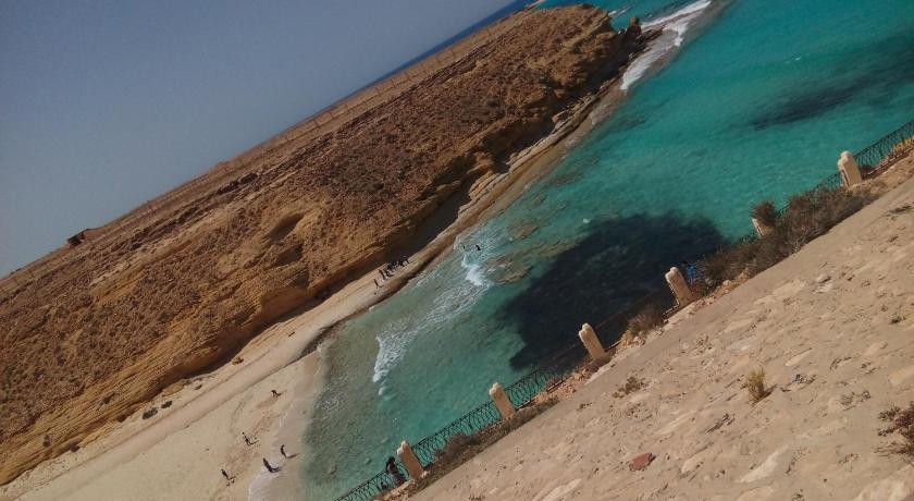 a sandy beach with a body of water, Negresco Hotel in Marsa Matruh