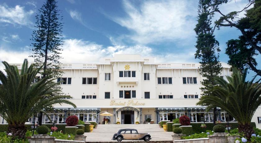 a large white building with a large clock on the top of it, Dalat Palace Heritage Hotel in Dalat